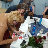 Kateřina Konečná se podepisuje účastníkům besedy na své fotografie a plakáty, na památku